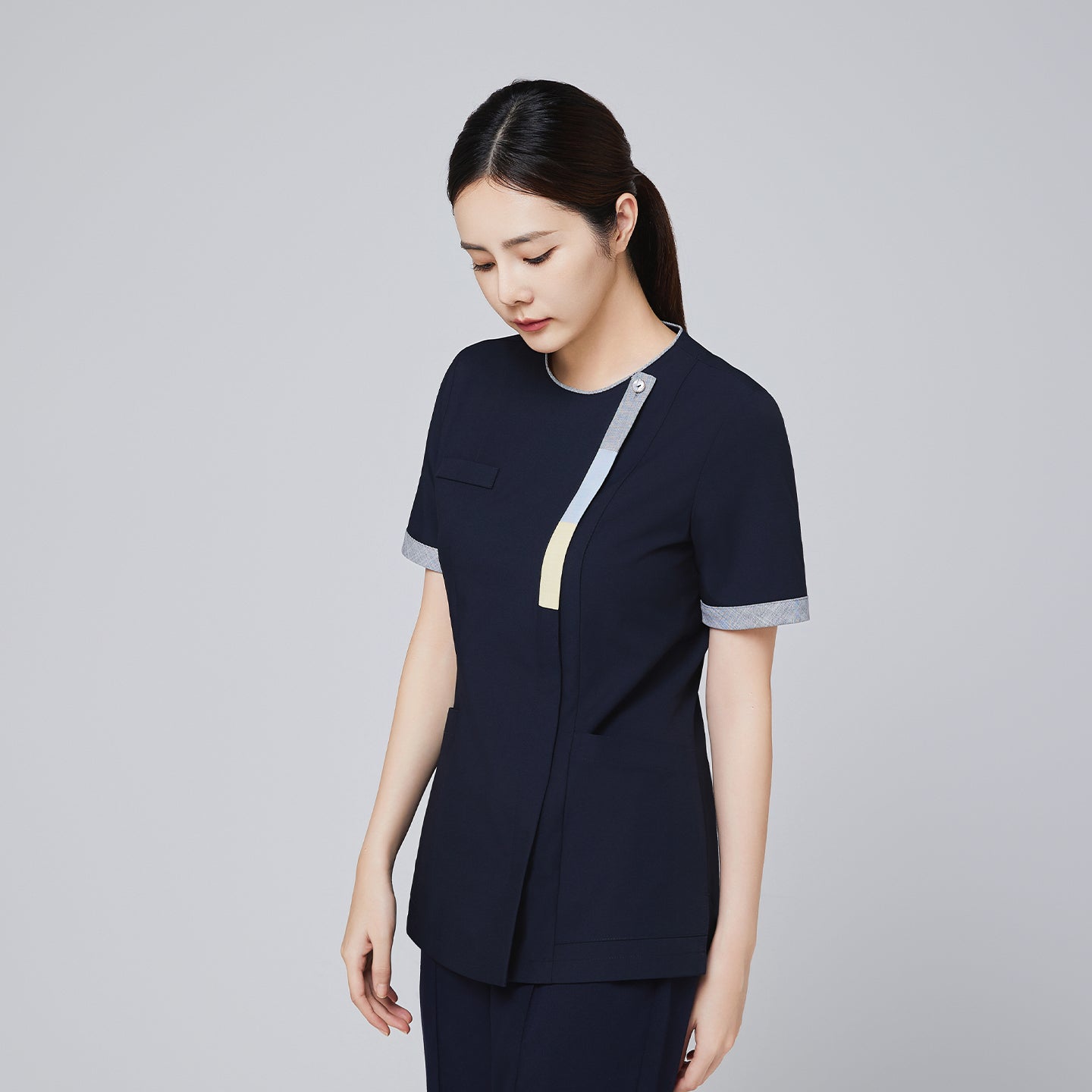 Image of Side view of navy scrub top with triple-tone front zipper and cuff detailing, designed for professional use,Eco Navy
